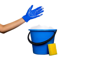 Plastic blue water bucket with soapsuds and black handle. Cleaning Products and Supplies. Gloved hand with soap suds. Isolated white background © mantisphoto