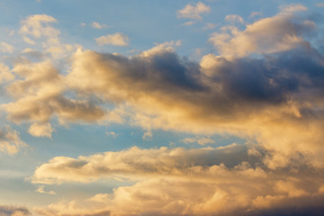 golden clouds on a blue sky at sunset. beautiful nature background. wonderful atmosphere scenery in the evening. cloudy forecast in the evening concept.