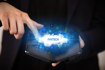 Businessman holding a foldable smartphone with FINTECH inscription, technology concept