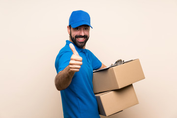 Delivery man with beard over isolated background with thumbs up because something good has happened