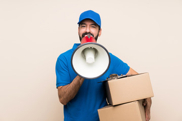 Delivery man with beard over isolated background shouting through a megaphone