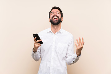 Young man with beard holding a mobile smiling a lot