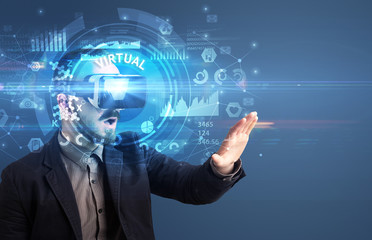 Businessman looking through Virtual Reality glasses with VIRTUAL inscription, innovative technology concept