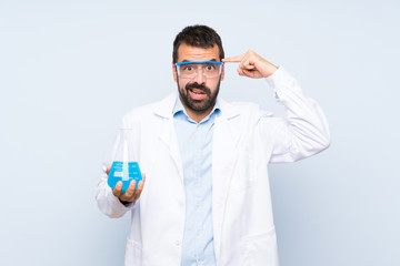 Young scientific holding laboratory flask over isolated background making the gesture of madness...
