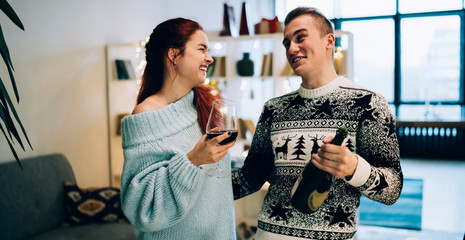 Pleased couple drinking wine hugging and feasting New Year