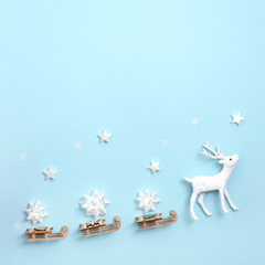 New year, Christmas frame, greeting card. Deer with Santa's sleigh, on pastel blue background. Top view, flat lay, copy space.
