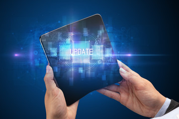 Businessman holding a foldable smartphone with UPDATE inscription, new technology concept