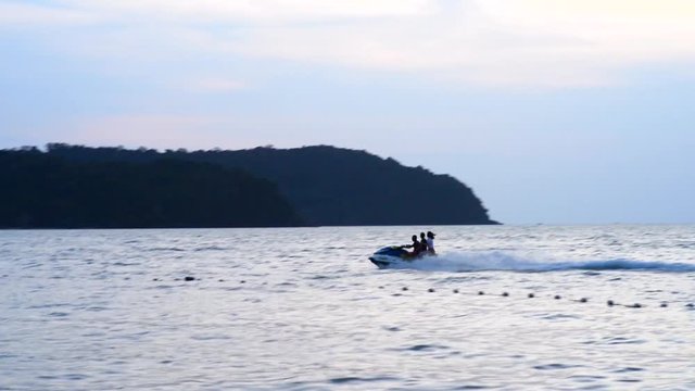 People ride a water bike on the sea at sunset