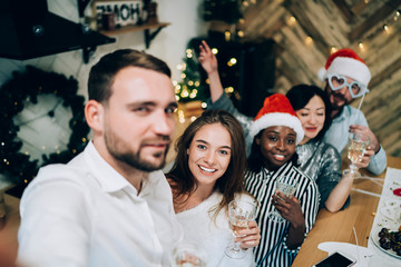 Happy friends with champagne taking selfie on Christmas eve