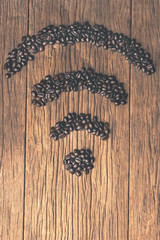 Coffee beans on old wooden table with copyspace. Coffee beans are arranged in the symbol wifi.