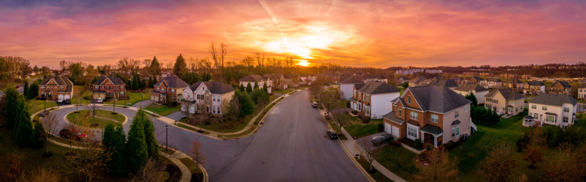 Aerial sunset panorama view of cul-de-sac (dead-end) luxury upscale residential neighborhood gated community street in Maryland USA, American real estate with single family homes brick facade 