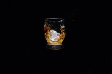 glass of whiskey and ice on black background