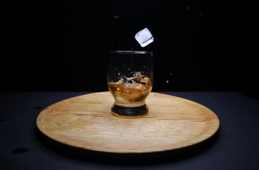 glass of whiskey and ice on black background