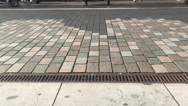 Slow motion of cyclists at a low angle cycling over a cobled street