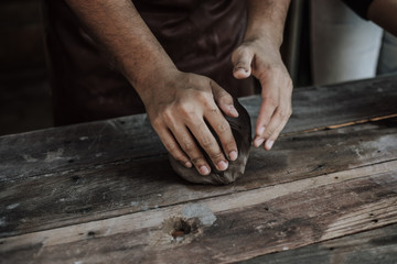 Craftsman hands close up, kneads and moistens the clay before work..