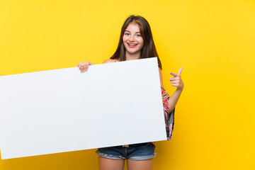 Fototapeta na wymiar Caucasian girl in colorful dress over isolated yellow background holding an empty white placard for insert a concept