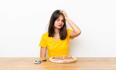 Caucasian girl with a pizza having doubts with confuse face expression