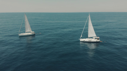 Aerial View of yacht in ocean. Drone footage of yachting around Balearic islands in the mediterranean sea. Silhouette of people