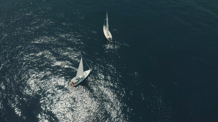 Naklejka premium Aerial View of yacht in ocean. Drone footage of yachting around Balearic islands in the mediterranean sea. Silhouette of people