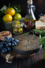 food frame made of wooden round boards, tangerines, olives, bottles of olive oil, grapes and honey. Vertical Image and Copy Space
