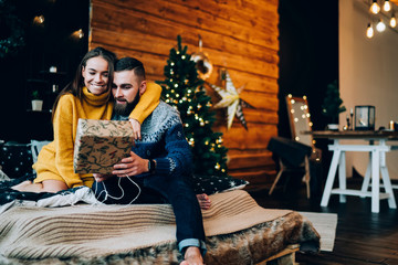 Young cheerful couple on bed with Christmas present