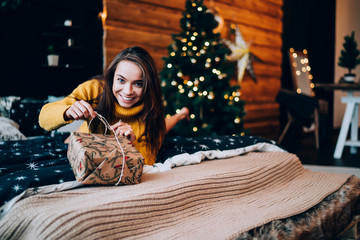 Obraz na płótnie Canvas Cheerful woman unwrapping Christmas present