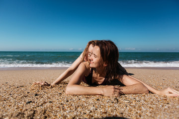 Fototapeta na wymiar Two young cheerful girlfriends women lie together on the seashore.