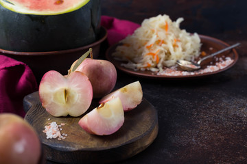 Homemade Soaked apples and watermelon, fermented cabbage on a dark background with bright linen textile. Horizontal Image and Copy Space
