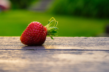 A strawberry on a picnic table.
