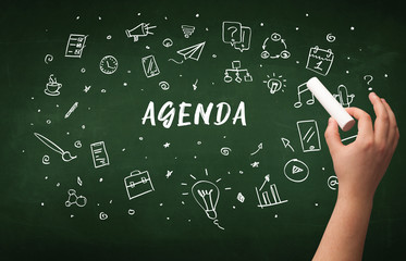 Hand drawing AGENDA inscription with white chalk on blackboard, education concept