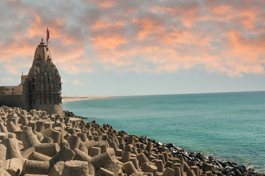 Lone hindu temple with flag on arabian sea coast with wave breakers