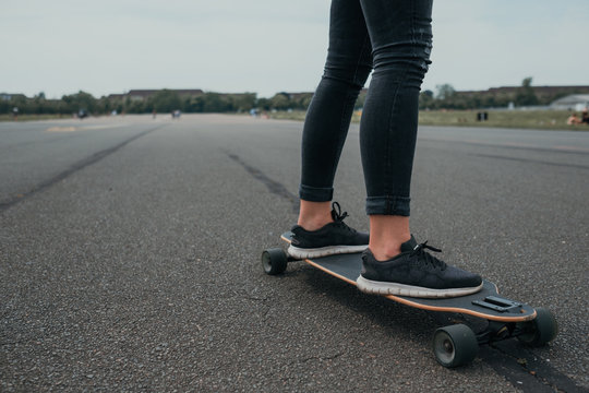 Closeup of woman's feet riding longboard on asphalt - Powered by Adobe