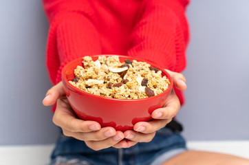 Young woman sitting on the floor and holding a bowl of cereals