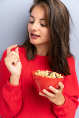 Young woman sitting on the floor and holding a bowl of cereals