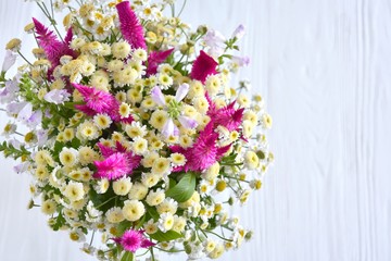 Gentle beautiful bouquet of wild flowers with white camomiles on blurred neutral background. Bunch of wildflowers. Romantic meadow flower with unusual violet fluffy flowers and camomile. Spring time 