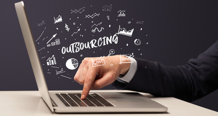 Businessman working on laptop with OUTSOURCING inscription, modern business concept