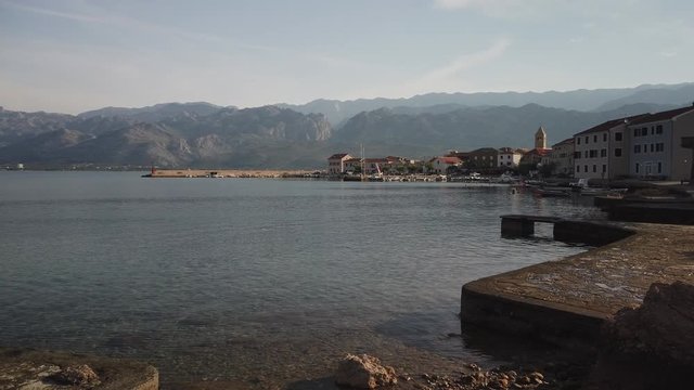 Slow evening pan of Croatian village and calm bay, mountains behind