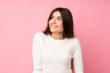 Fototapeta premium Young woman over isolated pink background laughing and looking up