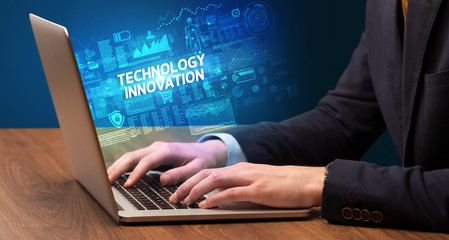 Businessman working on laptop with TECHNOLOGY INNOVATION inscription, cyber technology concept