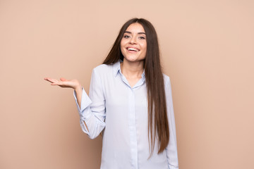 Young woman over isolated background holding copyspace imaginary on the palm to insert an ad