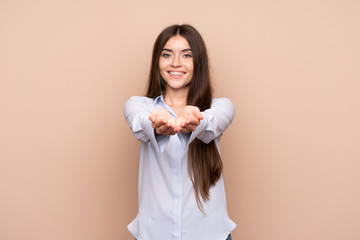 Young woman over isolated background holding copyspace imaginary on the palm to insert an ad