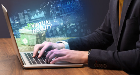 Obraz na płótnie Canvas Businessman working on laptop with VIRTUAL REALITY inscription, cyber technology concept