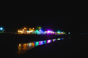 Some bars in Koh Lanta (Thailand) at night with their lights reflected on a small creek