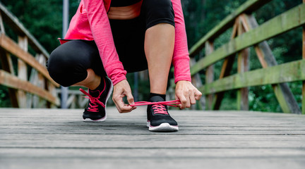 Fototapeta premium Sportswoman tying shoelace preparing to run outdoors