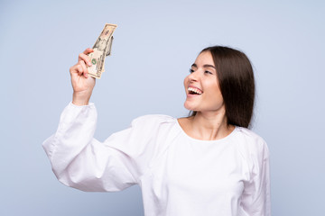 Young woman over isolated blue background taking a lot of money