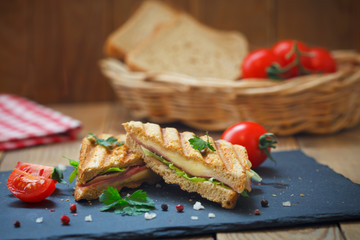 Club or toast sandwiches on black tray. Grilled sandwiches with salami, lettuce and melted cheese.