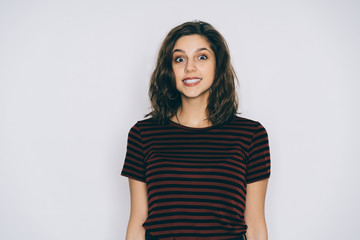 Smiling excited young beautiful woman in casual outfit posing in studio