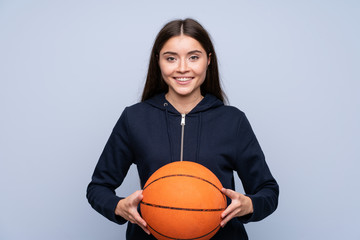 Young woman over isolated blue background with ball of basketball