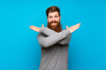 Redhead man with long beard over isolated blue background making NO gesture