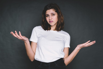 Contemporary woman with sceptical face holding arms sidewards